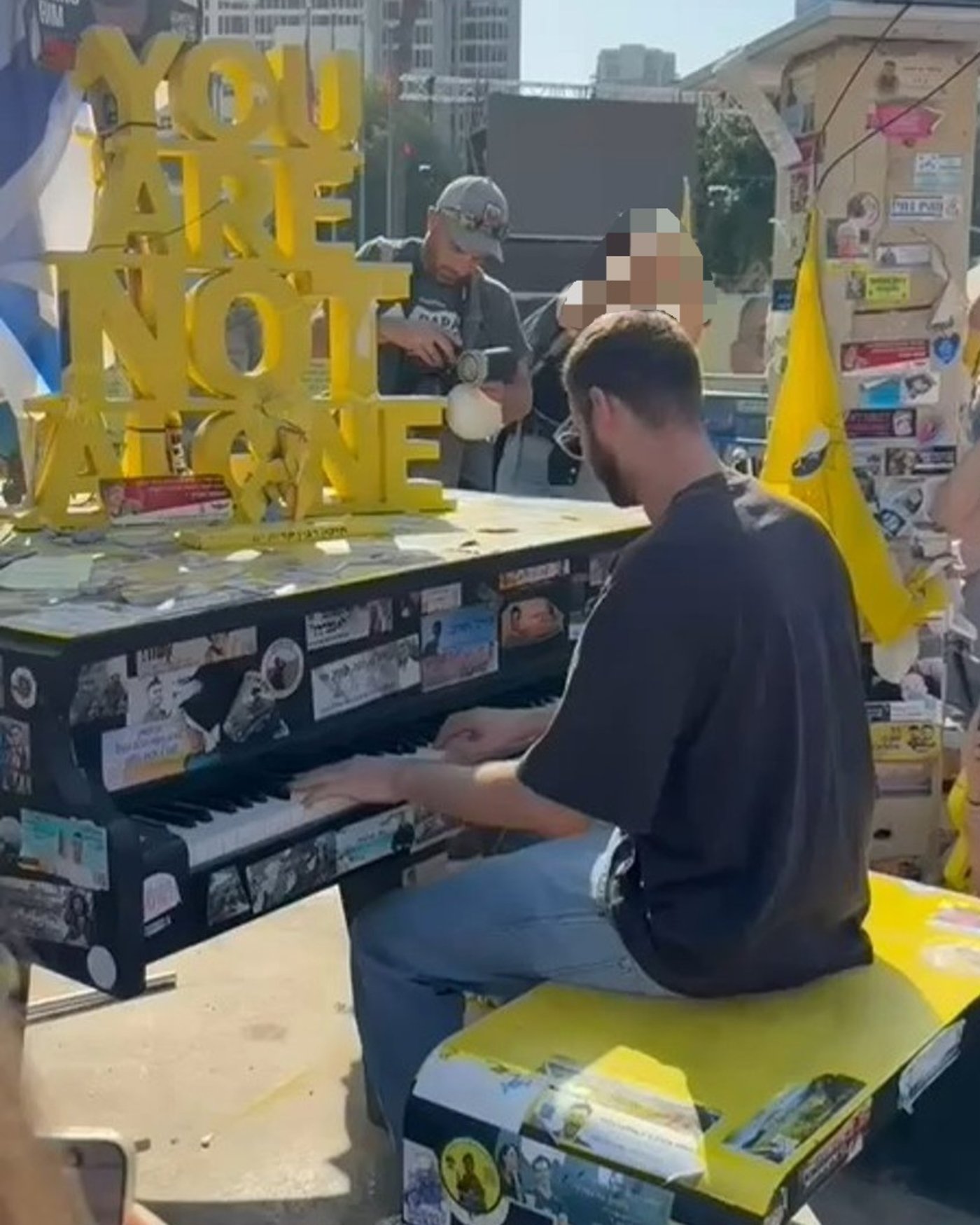 שורד השבי אלון אהל מנגן על פסנתר בכיכר החטופים