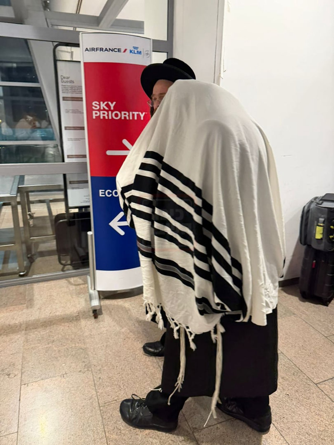רבי צבי מאיר זילברברג עטוף בטלית בשדה התעופה