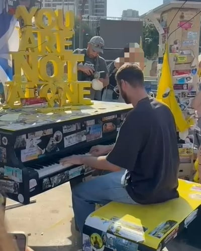 שורד השבי אלון אהל מנגן על פסנתר בכיכר החטופים