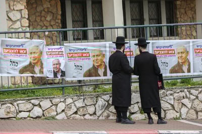 חרדים ליד כרזות של קמפיין בחירות מחוץ לקלפי