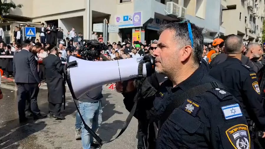 השוטר בזירה מנסה לפנות את ההמון בעזרת הכורז