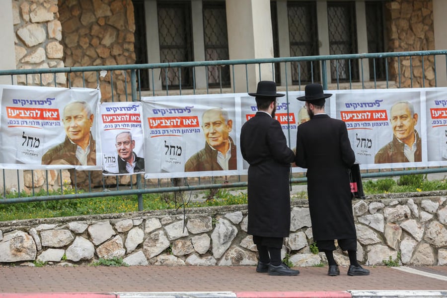 חרדים ליד כרזות של קמפיין בחירות מחוץ לקלפי