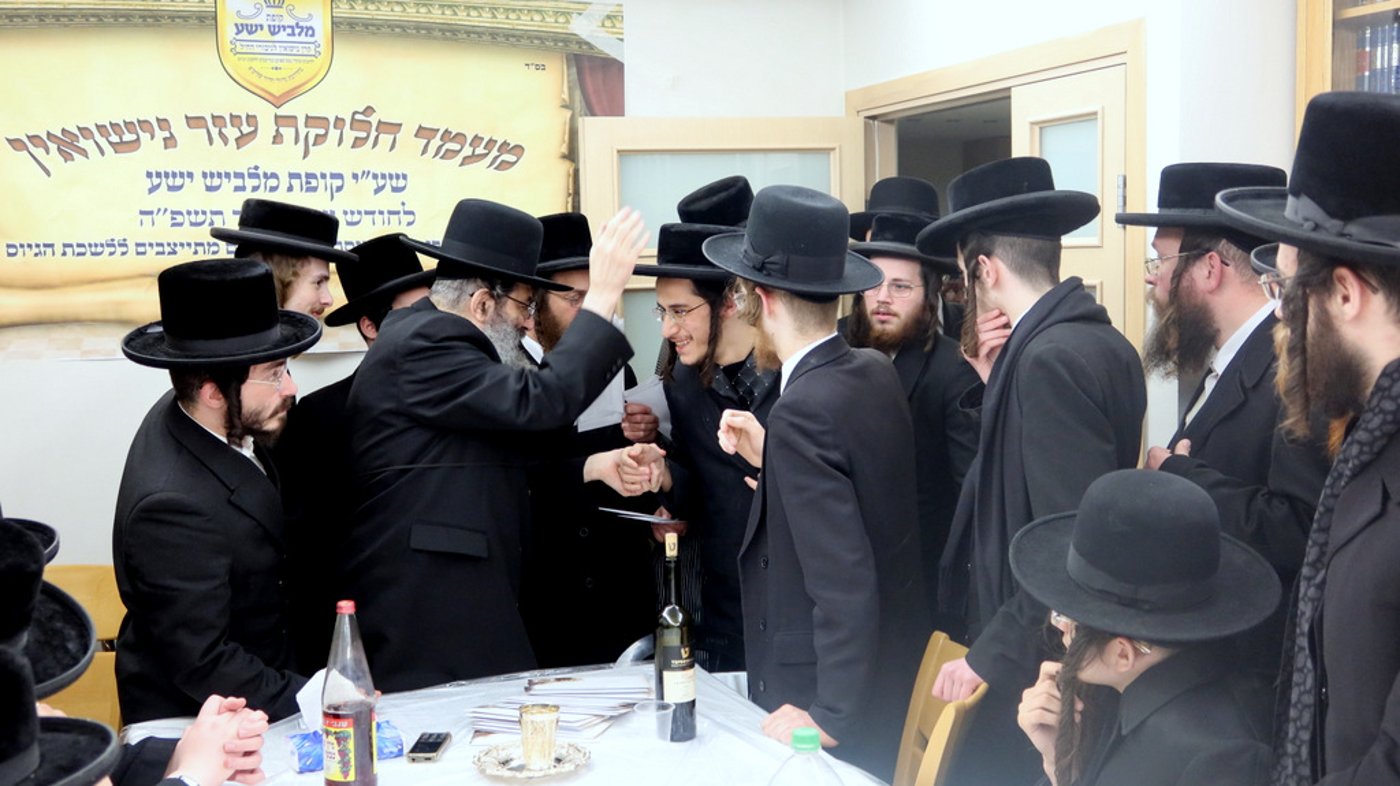 הגה"צ רבי צבי מאיר זילברברג בחלוקת שוברי השטריימלעך לחתנים