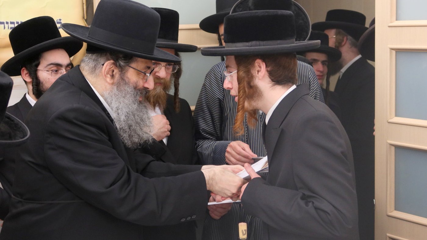 הגה"צ רבי צבי מאיר זילברברג בחלוקת שוברי השטריימלעך לחתנים