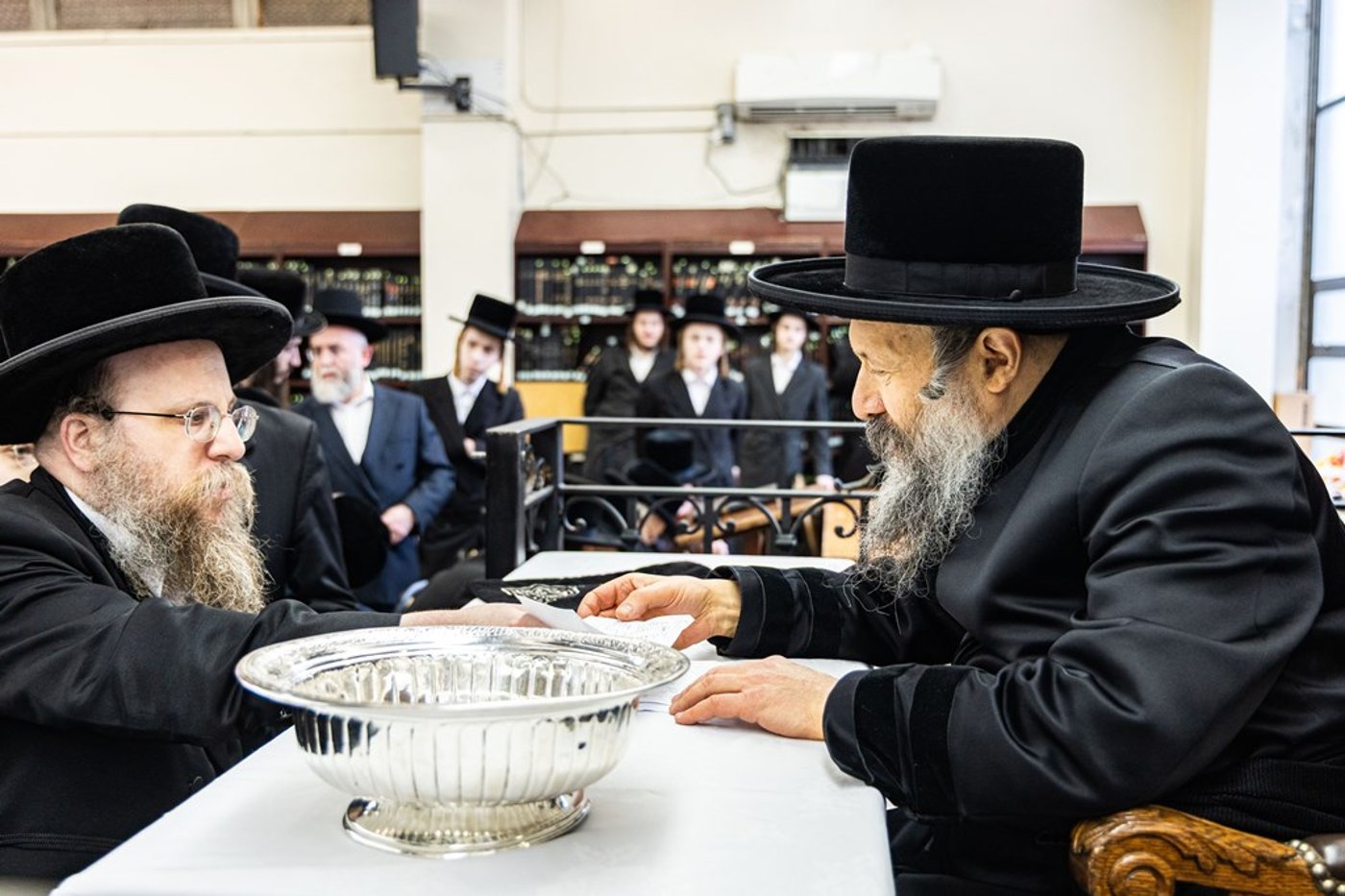 חסידי באבוב 45 נותנים קוויטלעך לרבם לפני המסע לצאנז