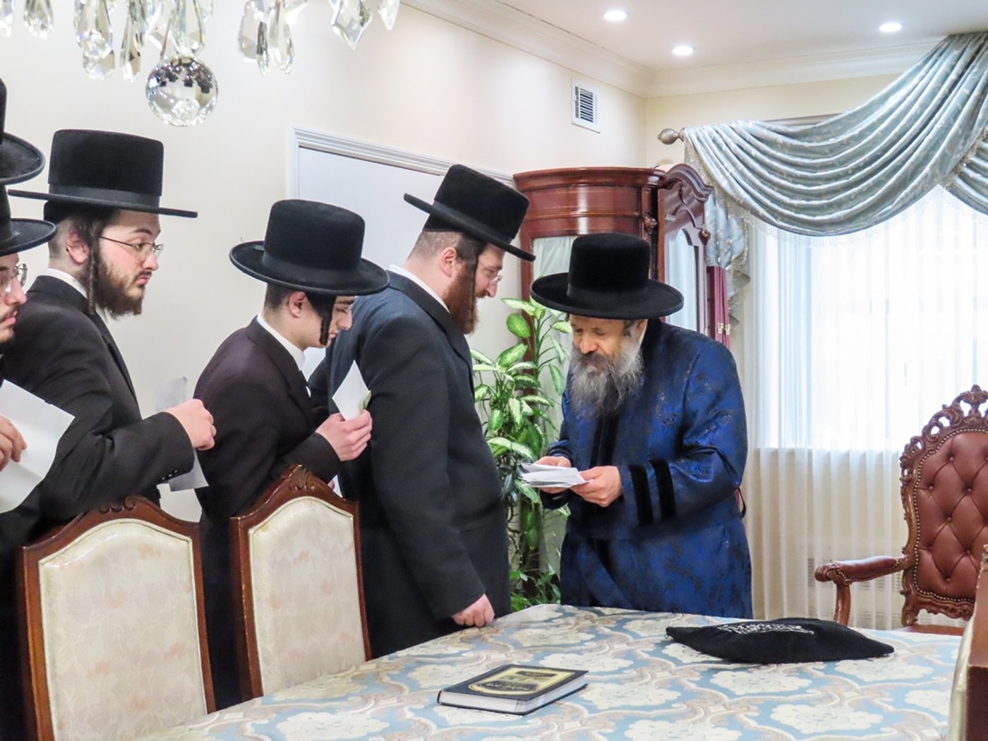 חסידי באבוב 45 נותנים קוויטלעך לרבם לפני המסע לצאנז
