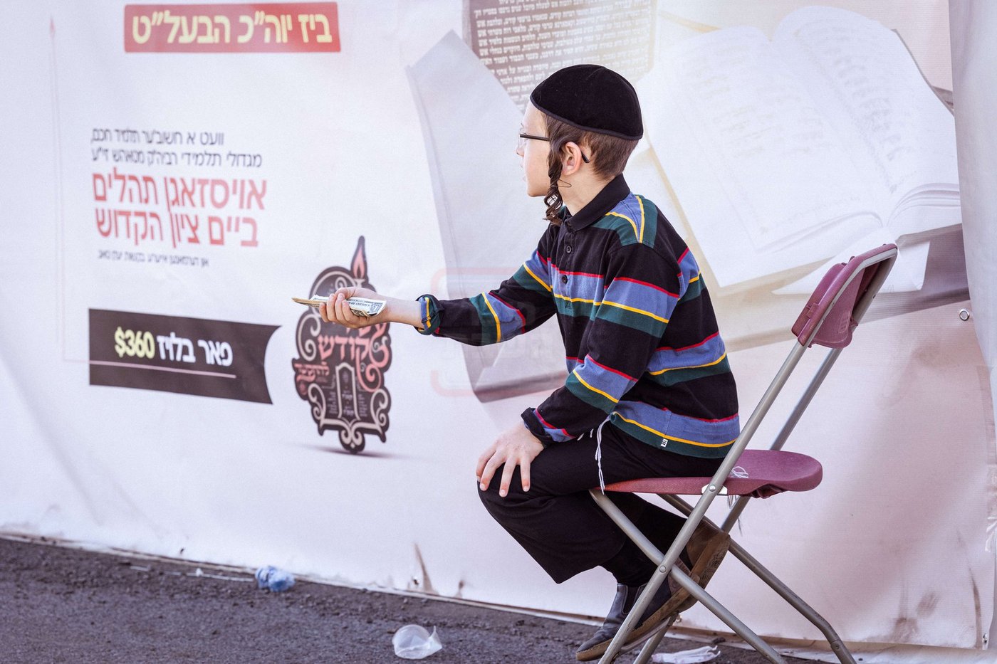 ילד חסידי מקבץ צדקה מחסידים בדרכם אל הציון הקדוש בטאהש