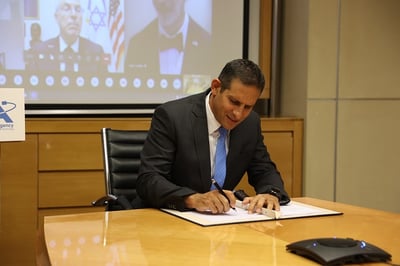 אורי אורון, מנהל סוכנות החלל הישראלית חותם על הסכם ארטמיס. מאחוריו בשידור, נציגי נאס"א